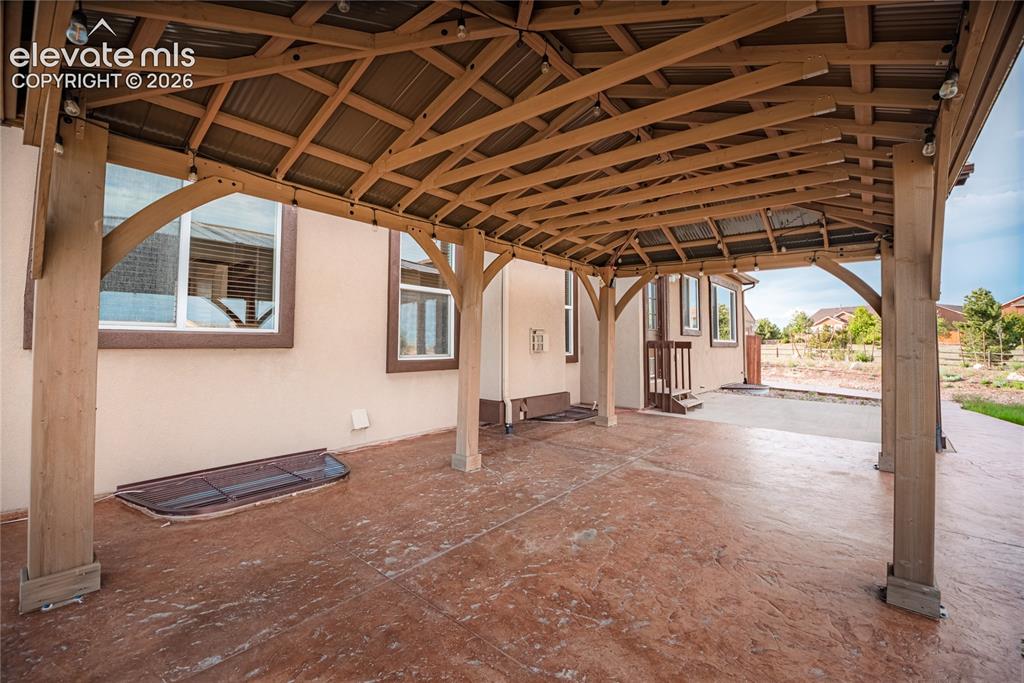 Image 44 of 48: Expansive covered patio featuring a stamped concrete surface, robust timber