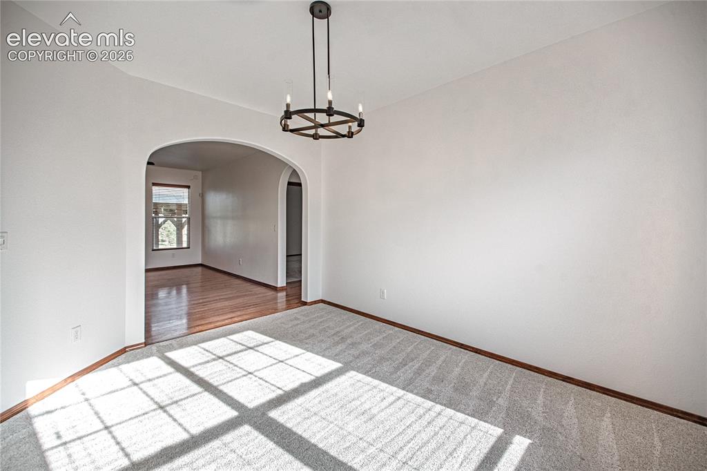 Image 6 of 38: Room featuring light-colored carpeting, a dark bronze-finish chandelier, an