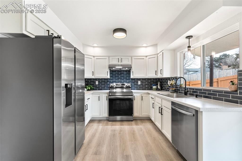 Image 14 of 49: Kitchen with stainless steel appliances, light countertops, under cabinet r