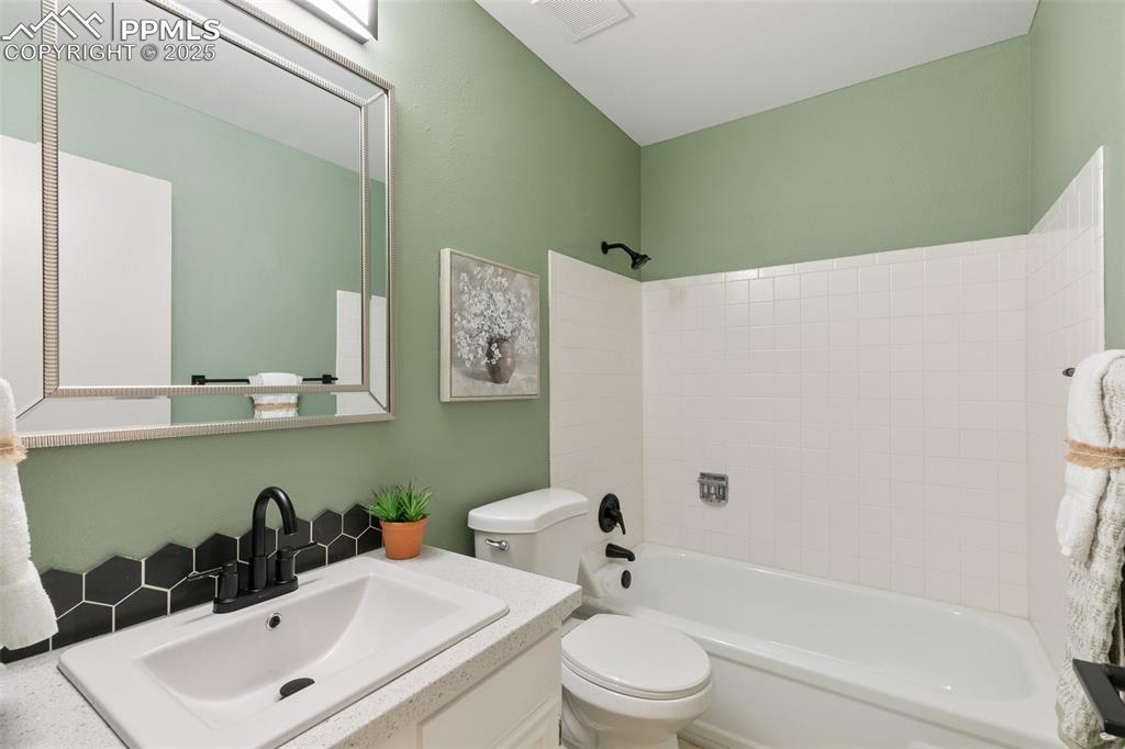 Image 30 of 49: Full bath featuring toilet, vanity, bathing tub / shower combination, visib