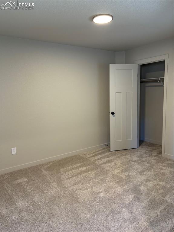 Image 11 of 16: Unfurnished bedroom with light colored carpet, a closet, and a textured cei