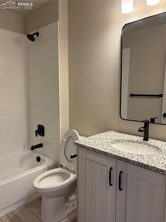 Image 13 of 16: Bathroom with vanity, shower / bathtub combination, and a textured wall
