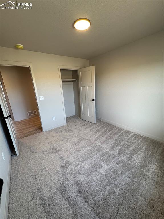 Image 15 of 16: Unfurnished bedroom with carpet, a closet, and a textured ceiling