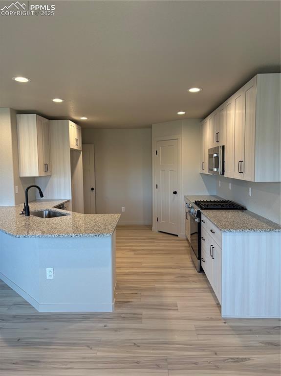 Image 4 of 16: Kitchen with light stone counters, range with gas cooktop, recessed lightin