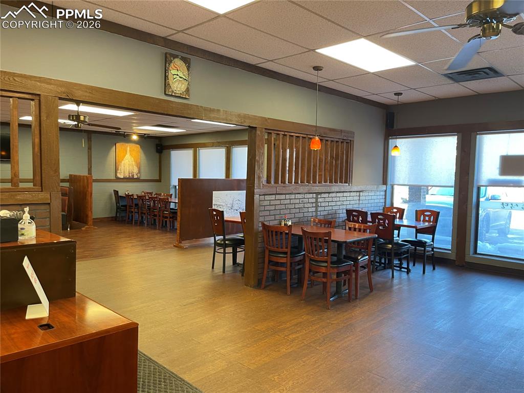 Image 5 of 9: Dining space with a paneled ceiling, a ceiling fan, and wood finished floor