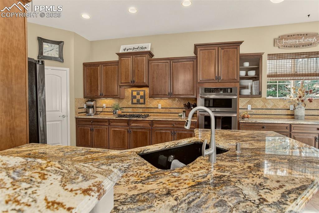Image 10 of 40: Kitchen featuring light stone countertops, tasteful backsplash, appliances