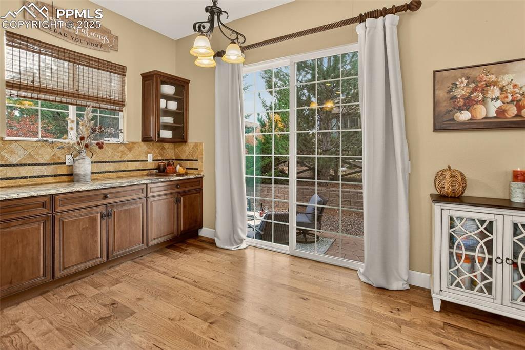 Image 14 of 40: Bar area with glass insert cabinets, hanging light fixtures, light stone co