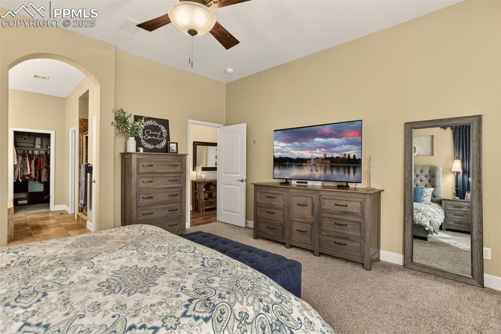 Image 19 of 40: Bedroom with arched walkways, light colored carpet, a walk in closet, and a