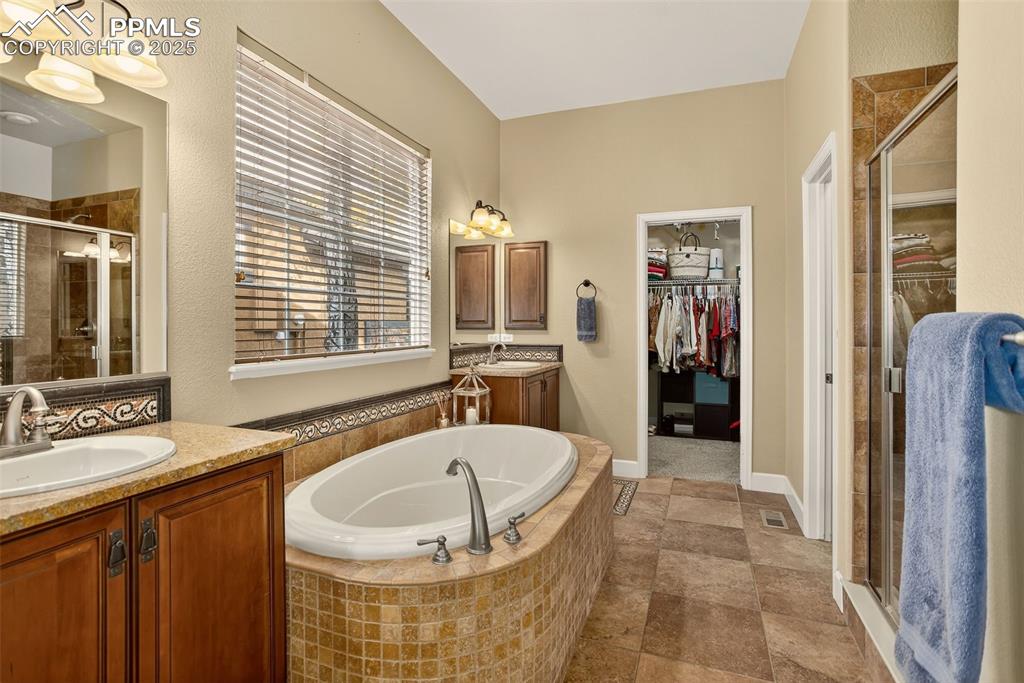 Image 20 of 40: Bathroom featuring a stall shower, two vanities, a bath, and a walk in clos