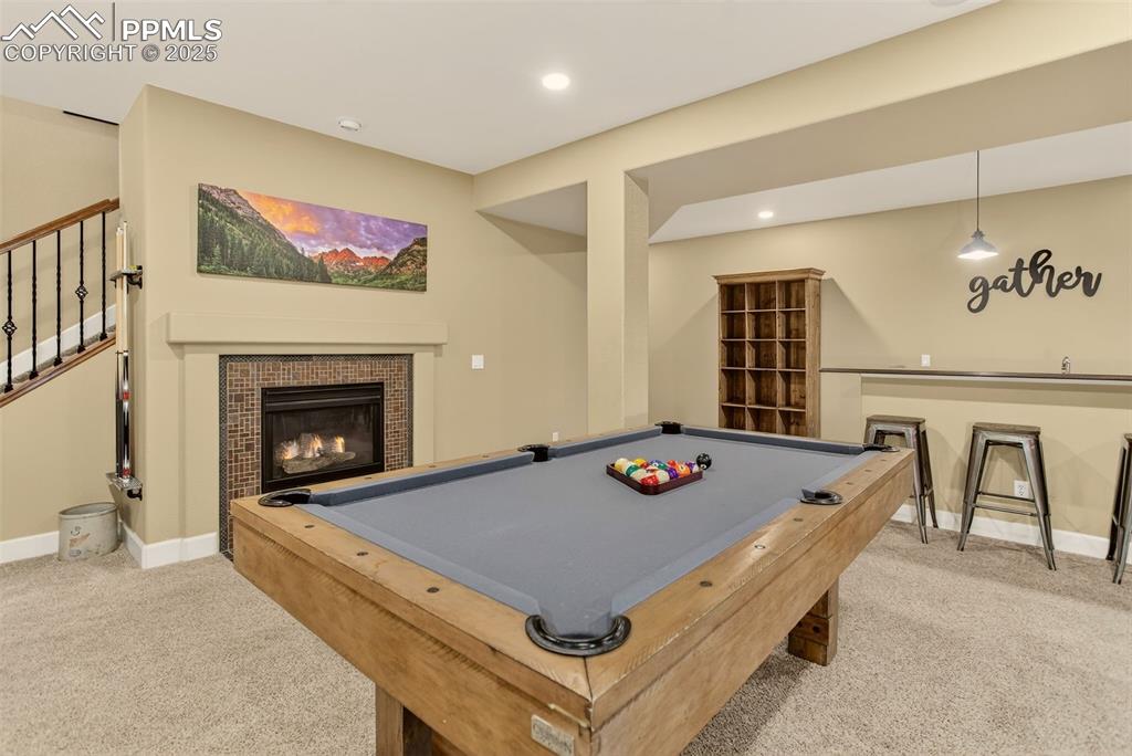 Image 22 of 40: Playroom with a tiled fireplace, light carpet, billiards, and recessed ligh