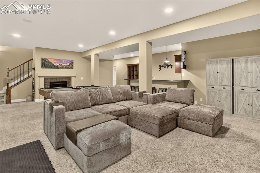 Image 25 of 40: Living area with light colored carpet, recessed lighting, a fireplace, stai