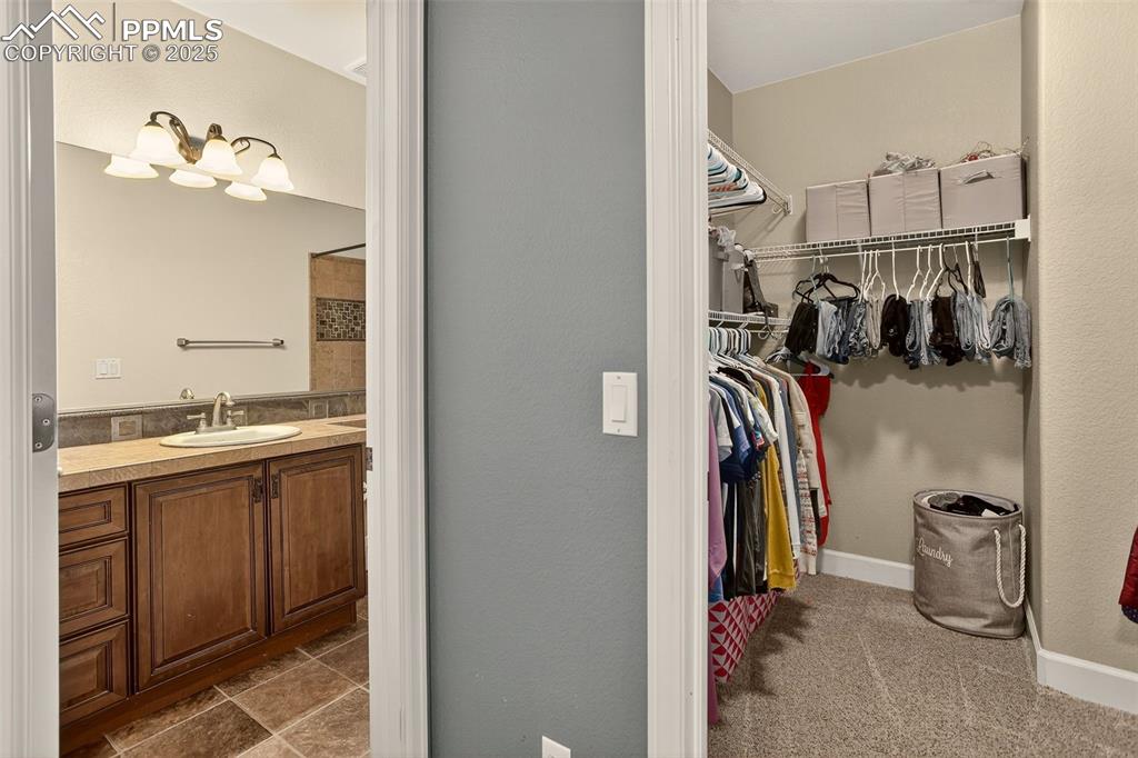 Image 28 of 40: Walk in closet featuring a sink and dark carpet