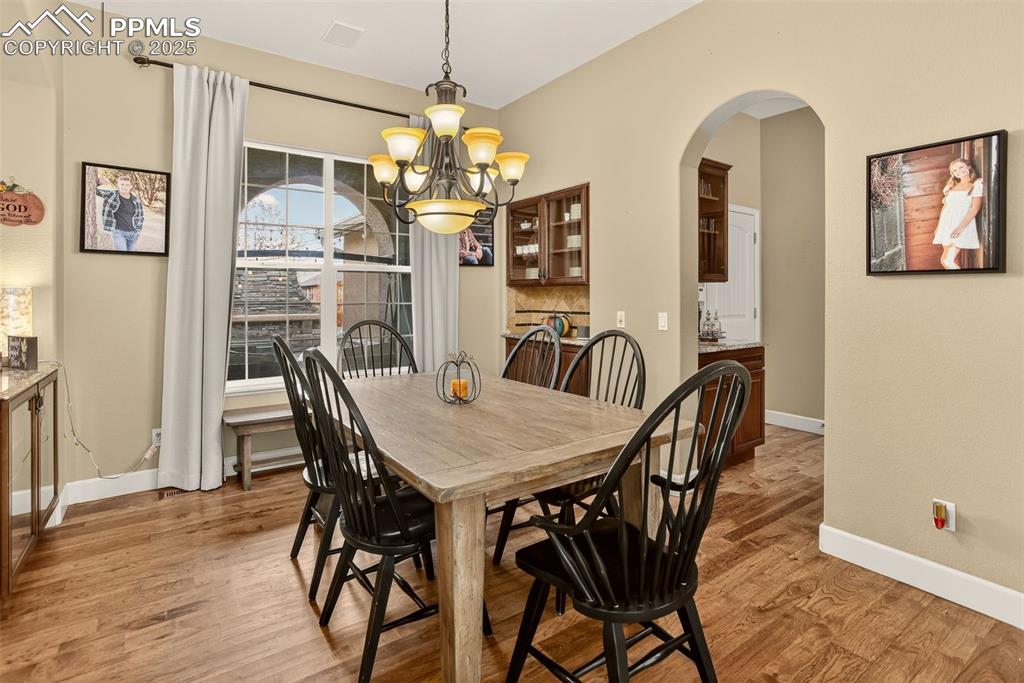 Image 5 of 40: Dining room with arched walkways, a chandelier, and light wood-style floori