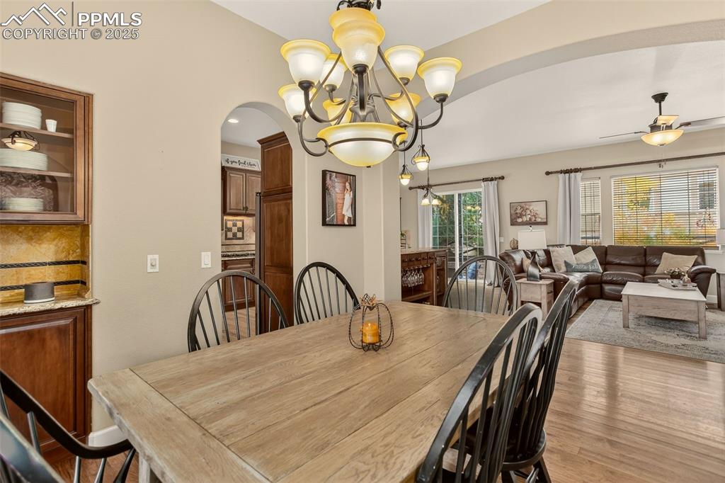 Image 6 of 40: Dining space featuring arched walkways, a chandelier, wood finished floors,