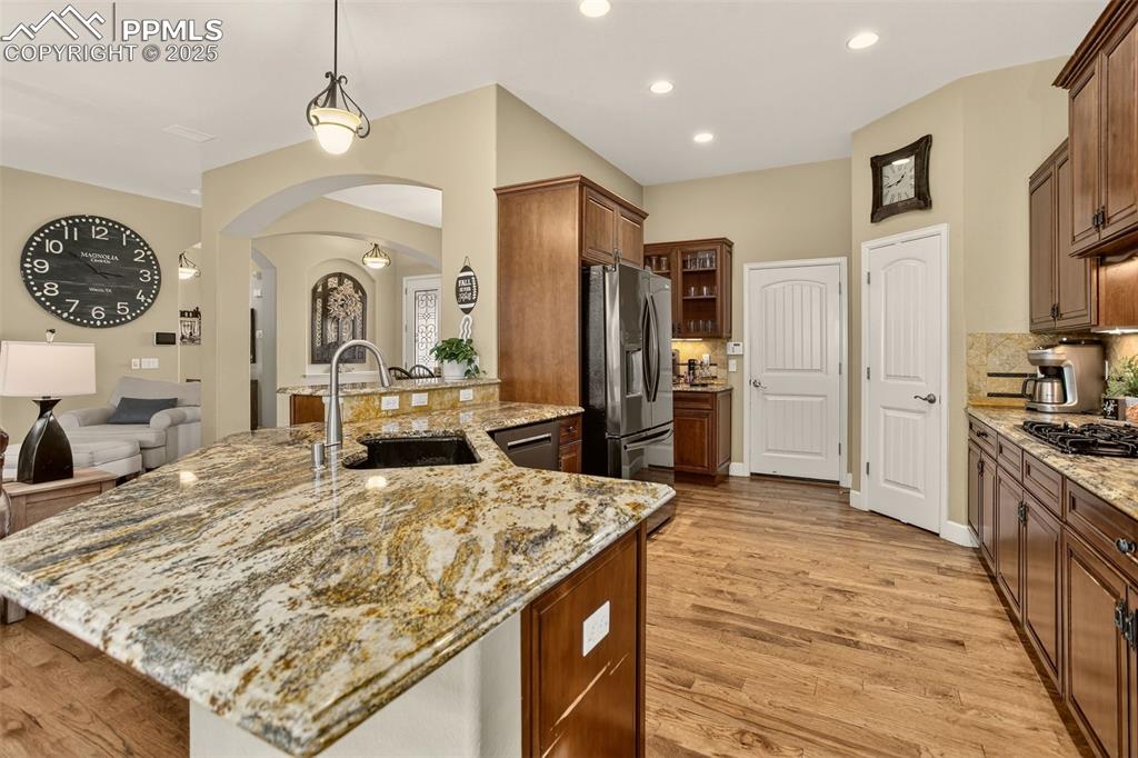 Image 7 of 40: Kitchen with arched walkways, pendant lighting, glass insert cabinets, appl