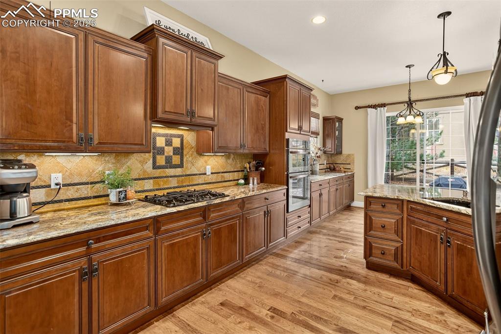 Image 8 of 40: Kitchen featuring backsplash, hanging light fixtures, light wood-style floo