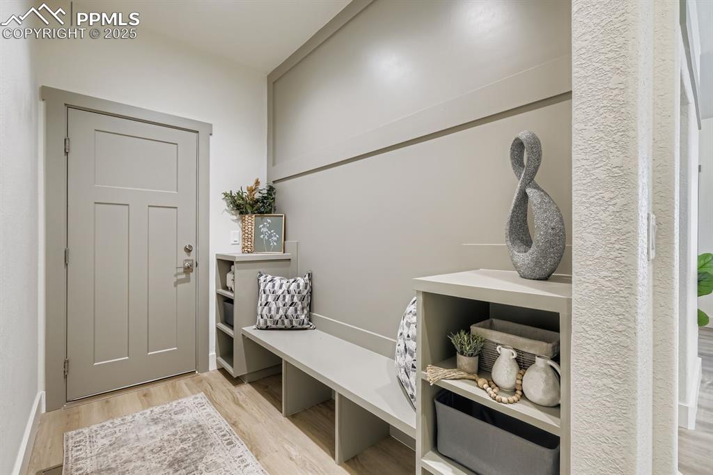 Image 14 of 41: Mudroom off the garage with built-in bench, cubbies, and hooks keeps daily