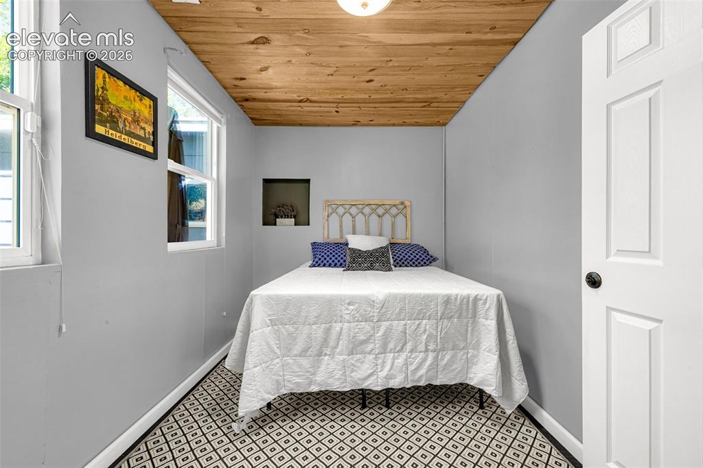Image 13 of 21: Compact room featuring a wood-panel ceiling, light gray walls, and geometri