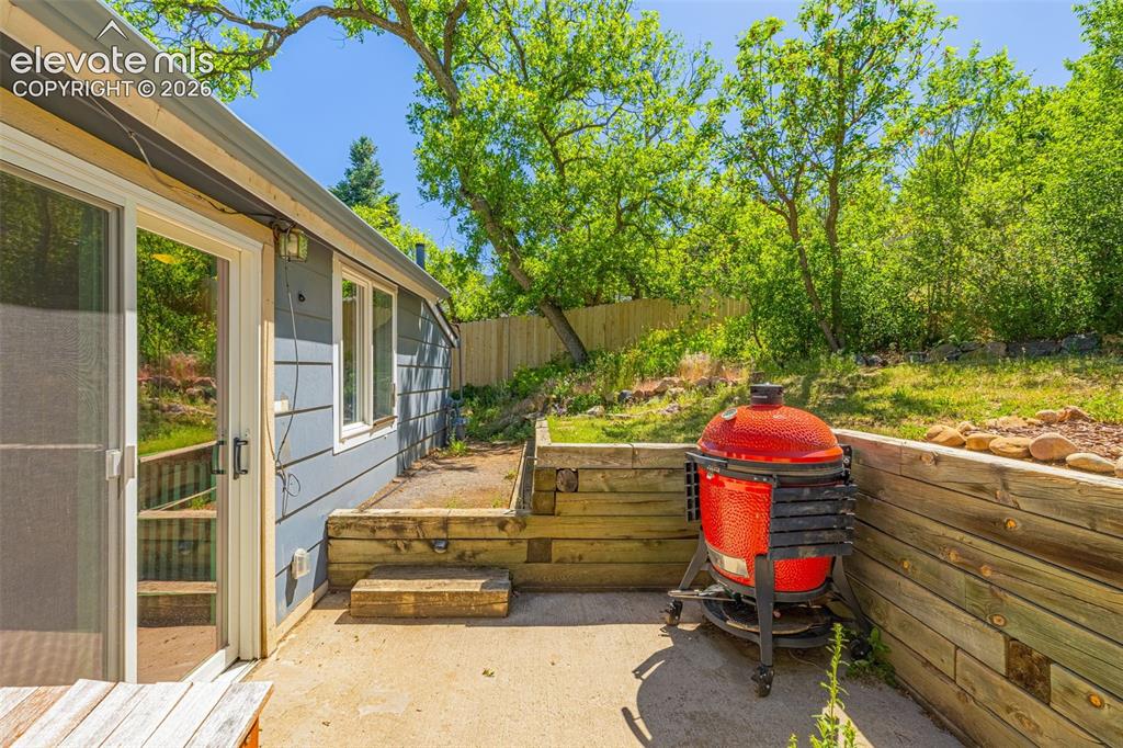 Image 15 of 21: Exterior patio with concrete flooring, wood retaining wall, and sliding gla
