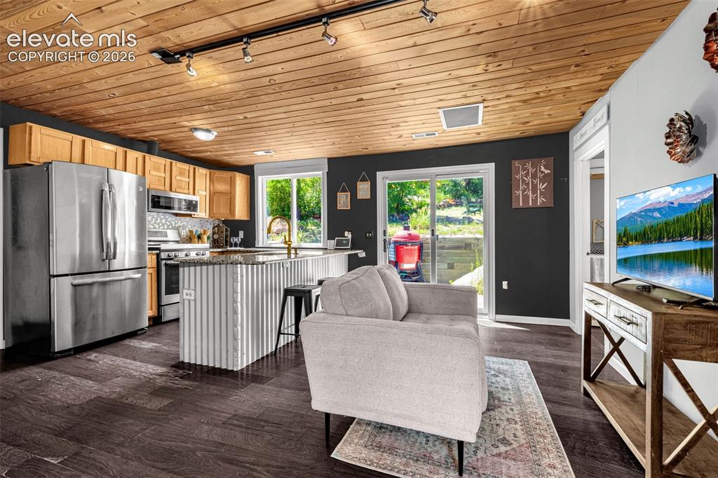 Image 6 of 21: Open-concept living space featuring wood-finish flooring, a wood-planked ce