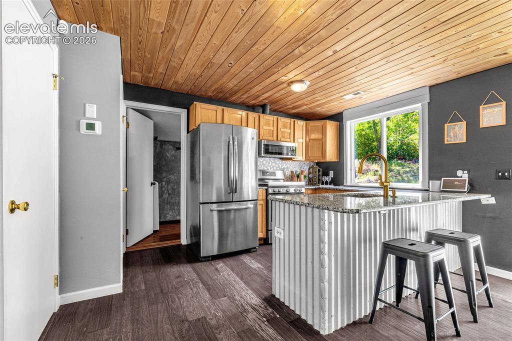 Image 8 of 21: Kitchen featuring wood-finish flooring, a plank wood ceiling, stainless ste