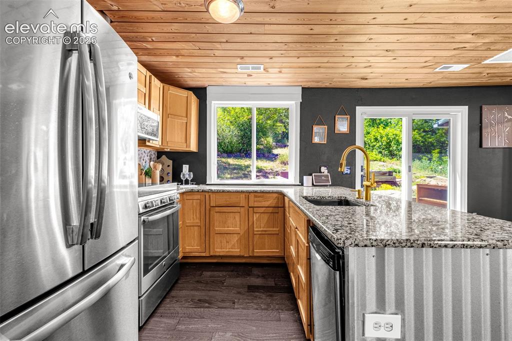 Image 9 of 21: Kitchen featuring stainless steel appliances, wood-finish flooring, natural