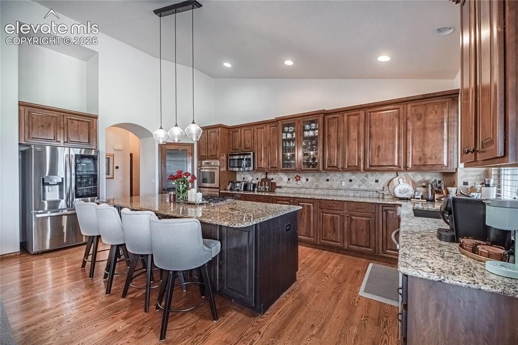Image 10 of 50: Kitchen featuring a large island with seating, stainless steel appliances,