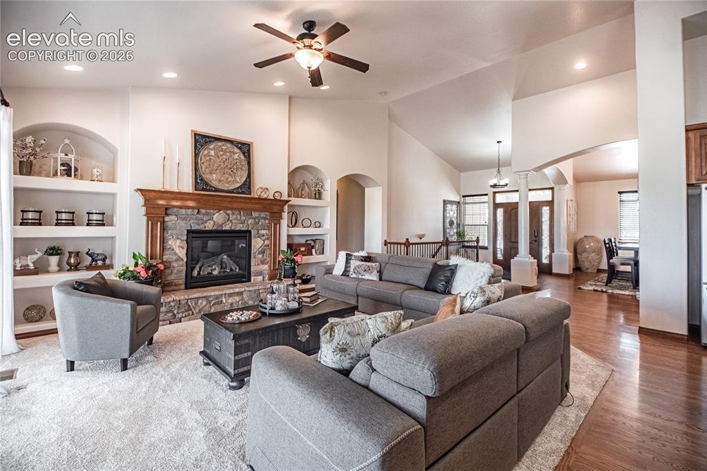 Image 11 of 50: Spacious living area featuring a stone fireplace with a wood mantel, built-