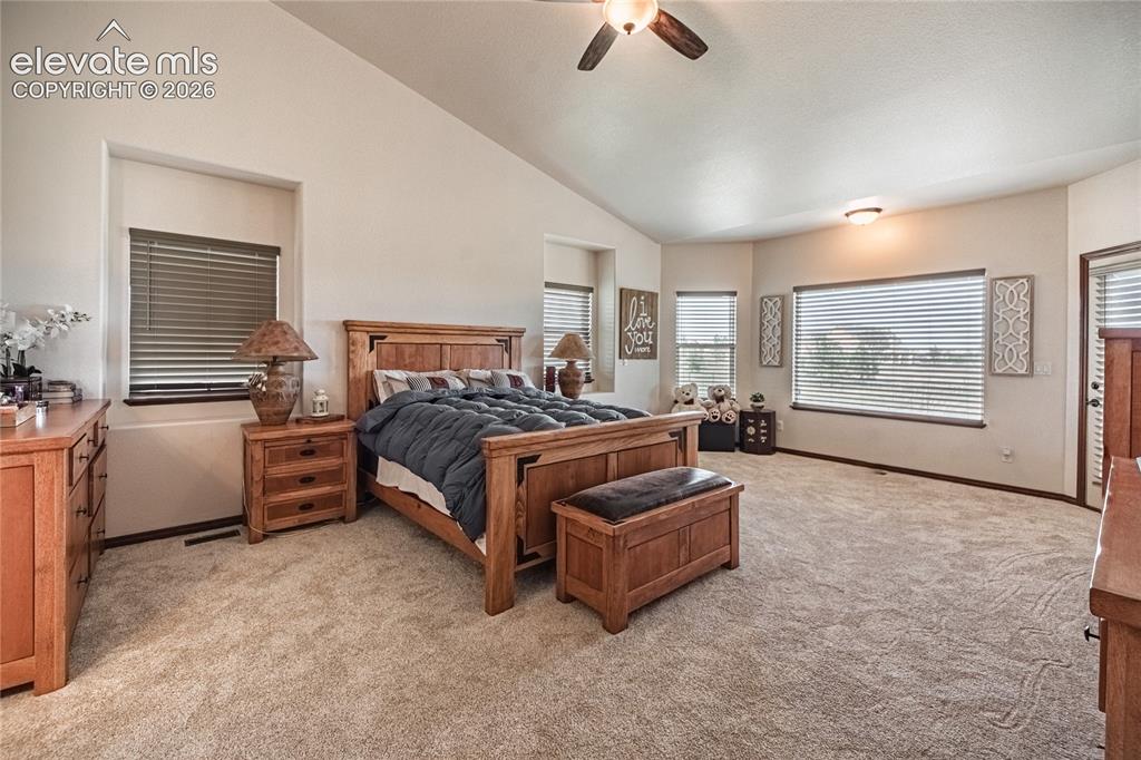 Image 13 of 50: Spacious bedroom featuring vaulted ceilings, a ceiling fan, and light-toned