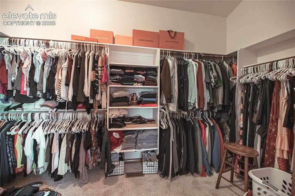 Image 16 of 50: Walk-in closet featuring extensive built-in shelving, multiple hanging rods