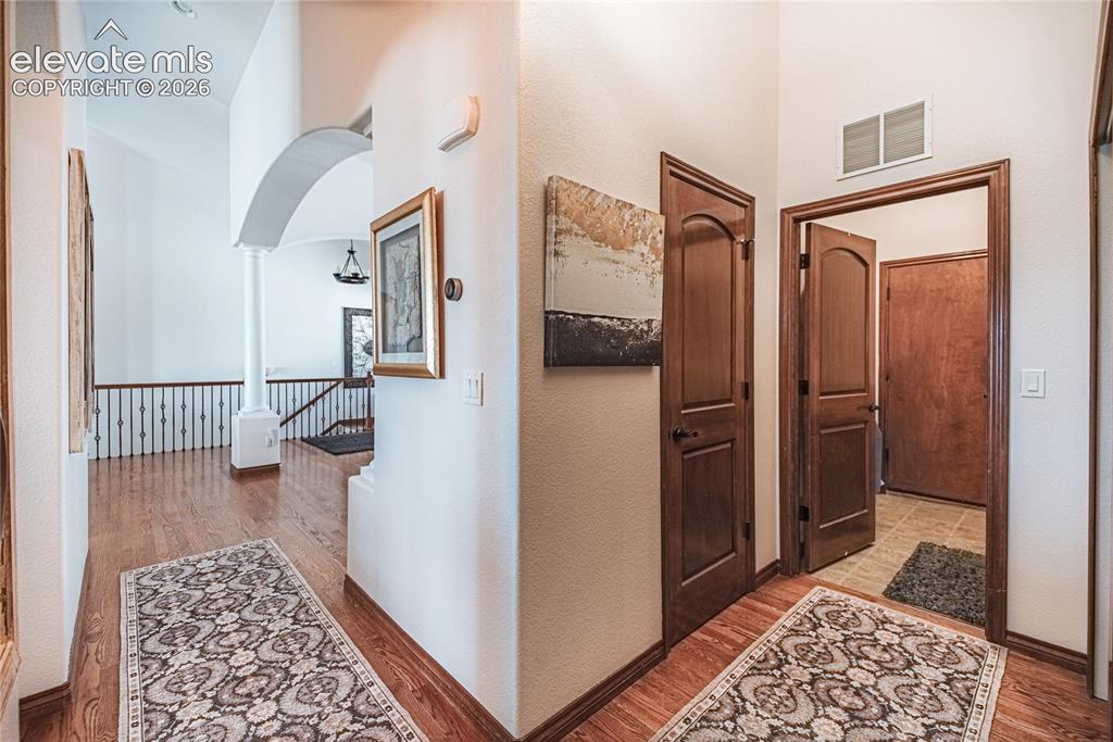 Image 17 of 50: Hallway featuring wood-finish flooring, white walls, dark wood doors, and a