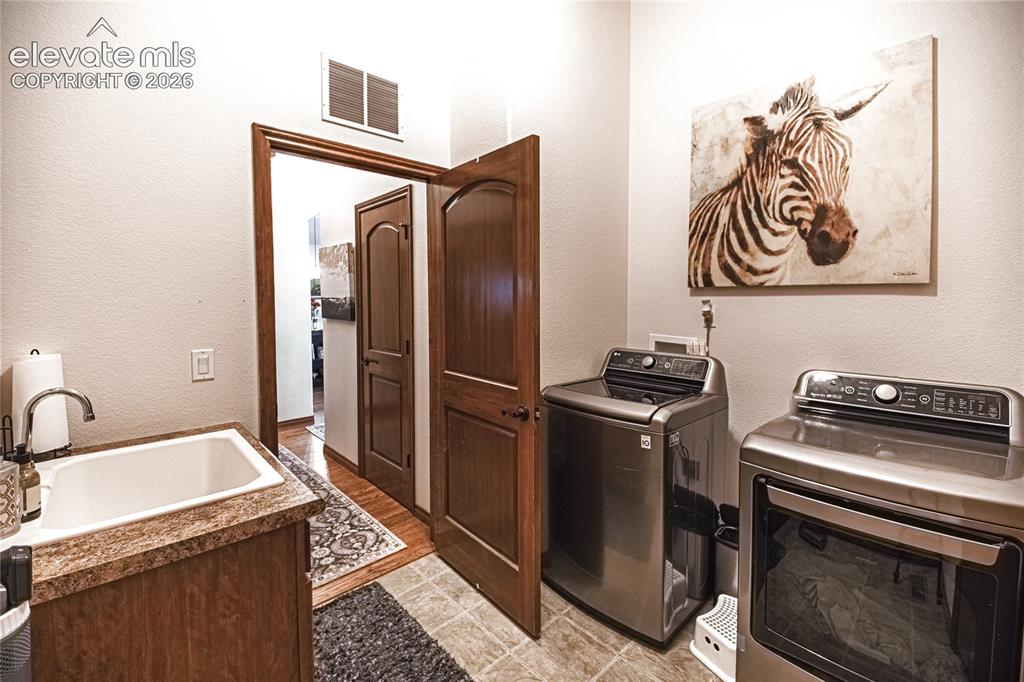 Image 18 of 50: Dedicated laundry area featuring a utility sink with a high-arc faucet, woo