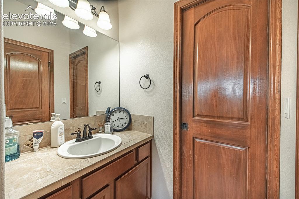 Image 21 of 50: Bathroom vanity featuring a tile countertop, integrated sink, and bronze-fi