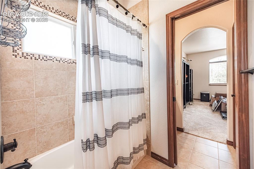 Image 24 of 50: Bathroom featuring tile shower surround with decorative mosaic accent, wind