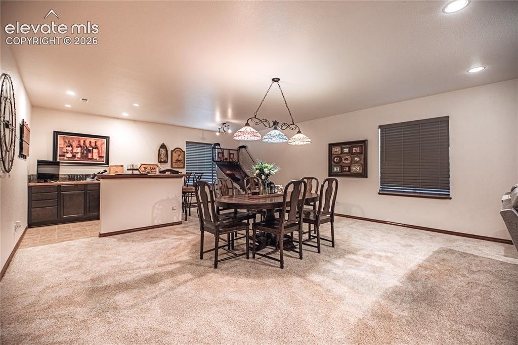 Image 27 of 50: Spacious entertainment area featuring recessed lighting, a built-in wet bar