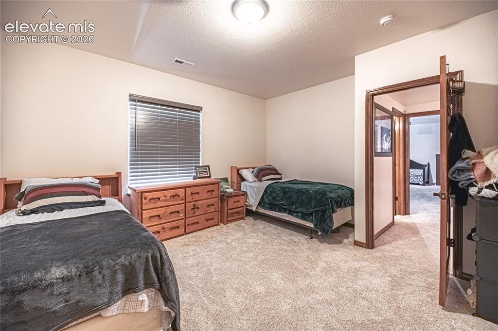 Image 32 of 50: Carpeted room with a ceiling-mounted light fixture and horizontal blinds