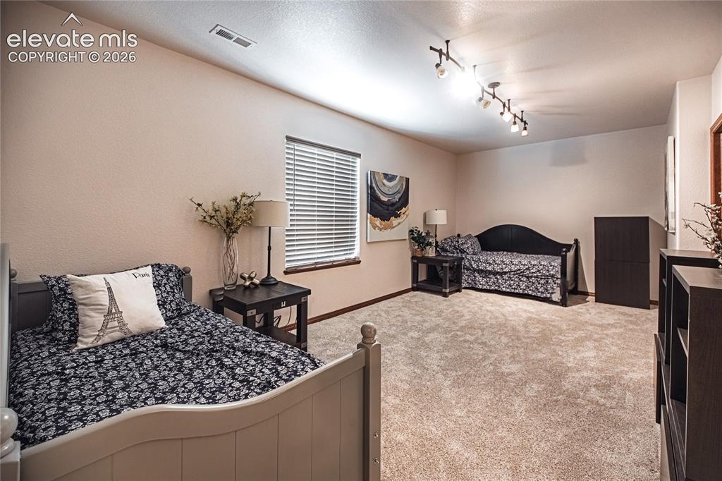 Image 33 of 50: Spacious room featuring neutral carpeting, a large window with blinds, and
