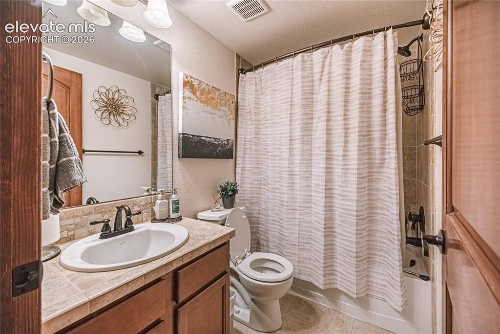 Image 35 of 50: Bathroom featuring a wood-finish vanity with an integrated sink and bronzed