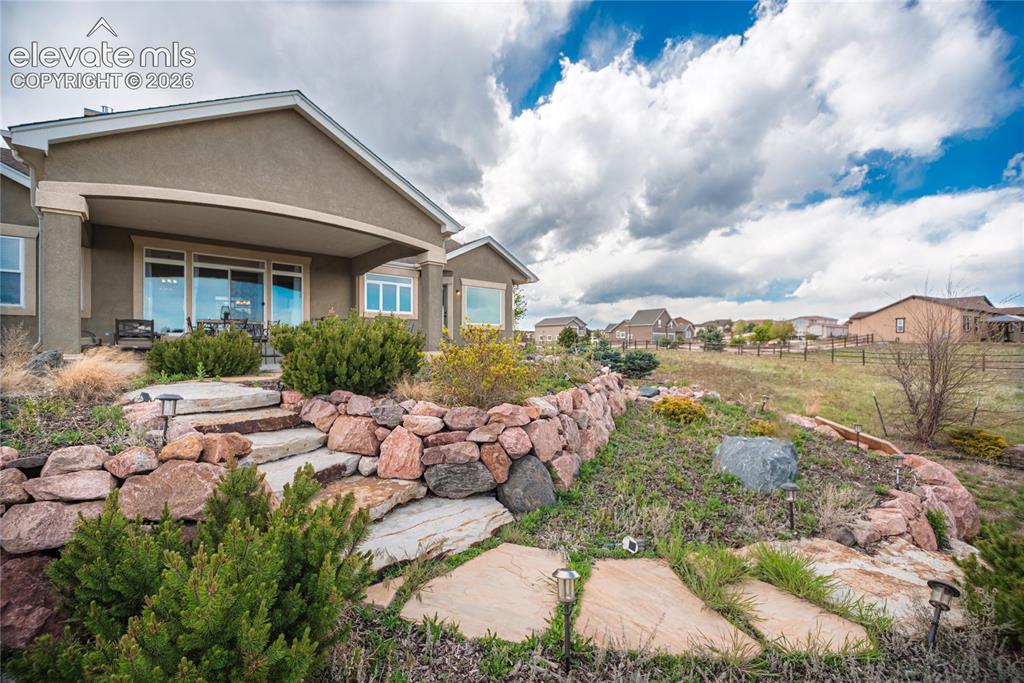 Image 38 of 50: Terraced backyard featuring stone retaining walls, natural stone steps, and
