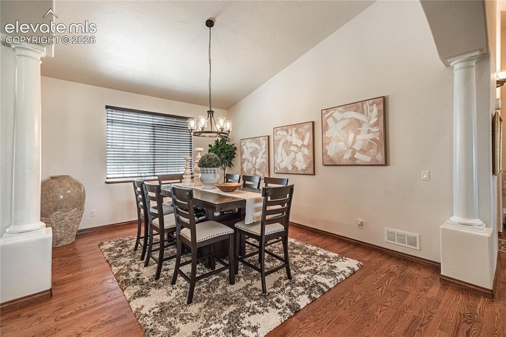 Image 4 of 50: Spacious dining area featuring wood-finish flooring, a vaulted ceiling, and