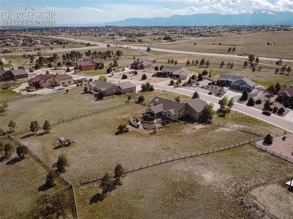 Image 47 of 50: Expansive property featuring a large fenced lot, mature trees, and mountain