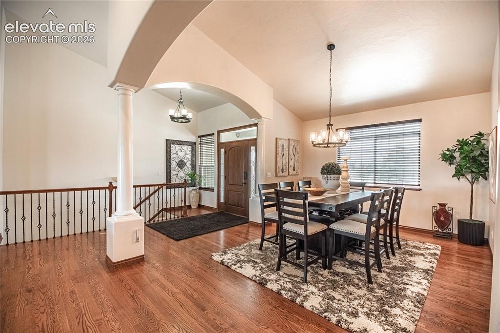 Image 5 of 50: Formal dining area with wood-finish flooring, a contemporary chandelier, an
