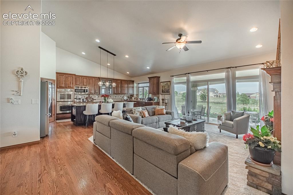Image 7 of 50: Open-concept living space with vaulted ceilings, wood-finish flooring, and