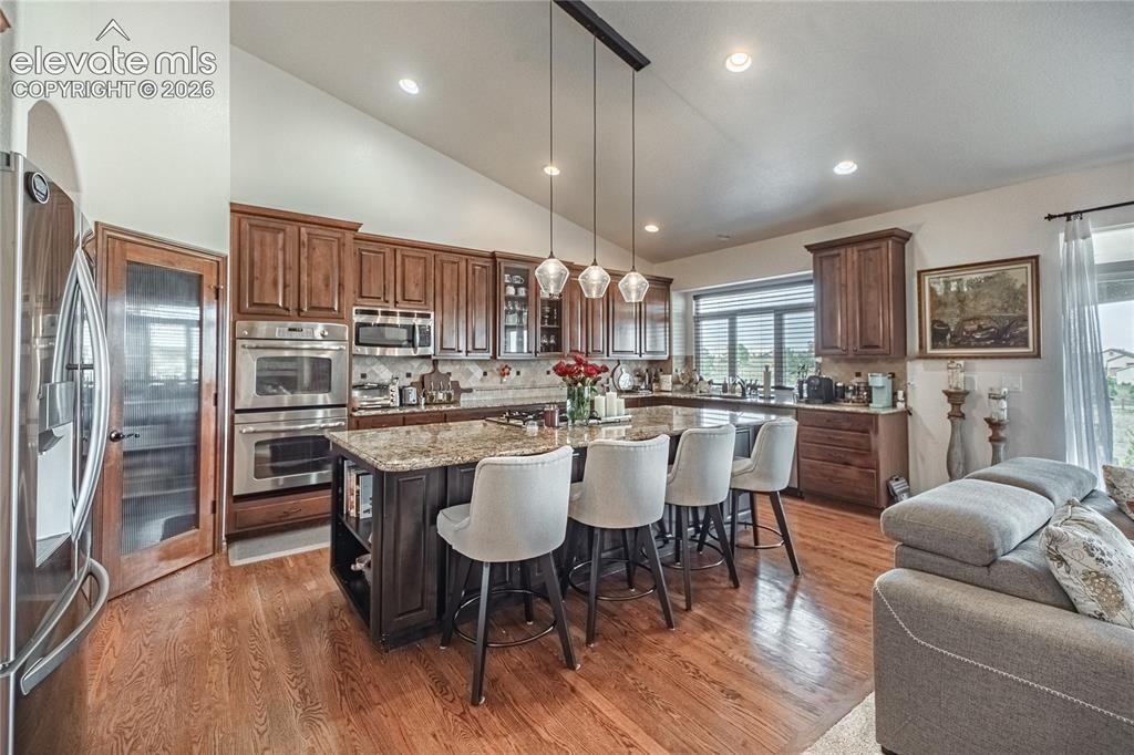 Image 8 of 50: Expansive kitchen featuring wood-finish flooring, a large island with a sto