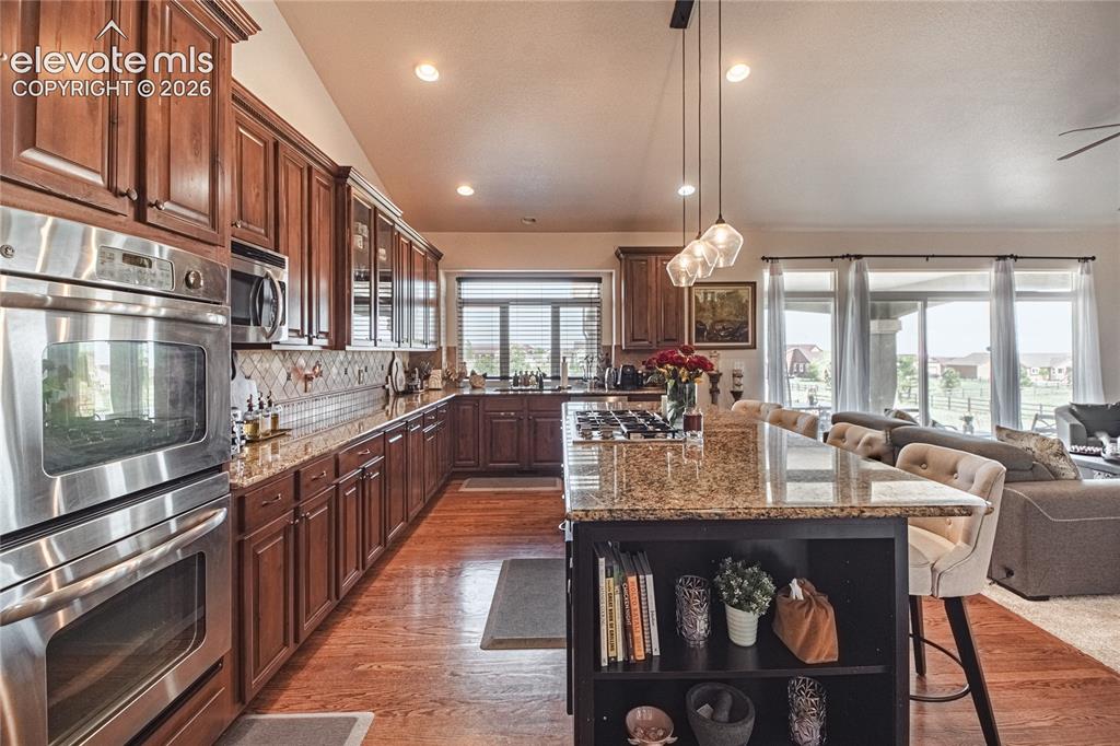 Image 9 of 50: Open-concept kitchen featuring wood-finish flooring, rich wood cabinetry, s