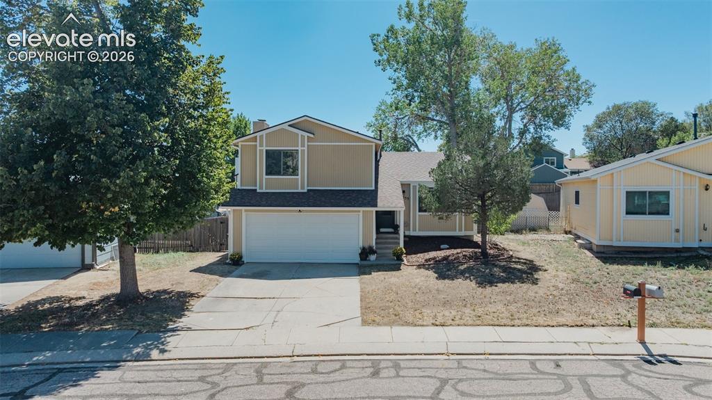 Image 1 of 33: Split-level residence featuring a two-car garage, mature trees, and a concr
