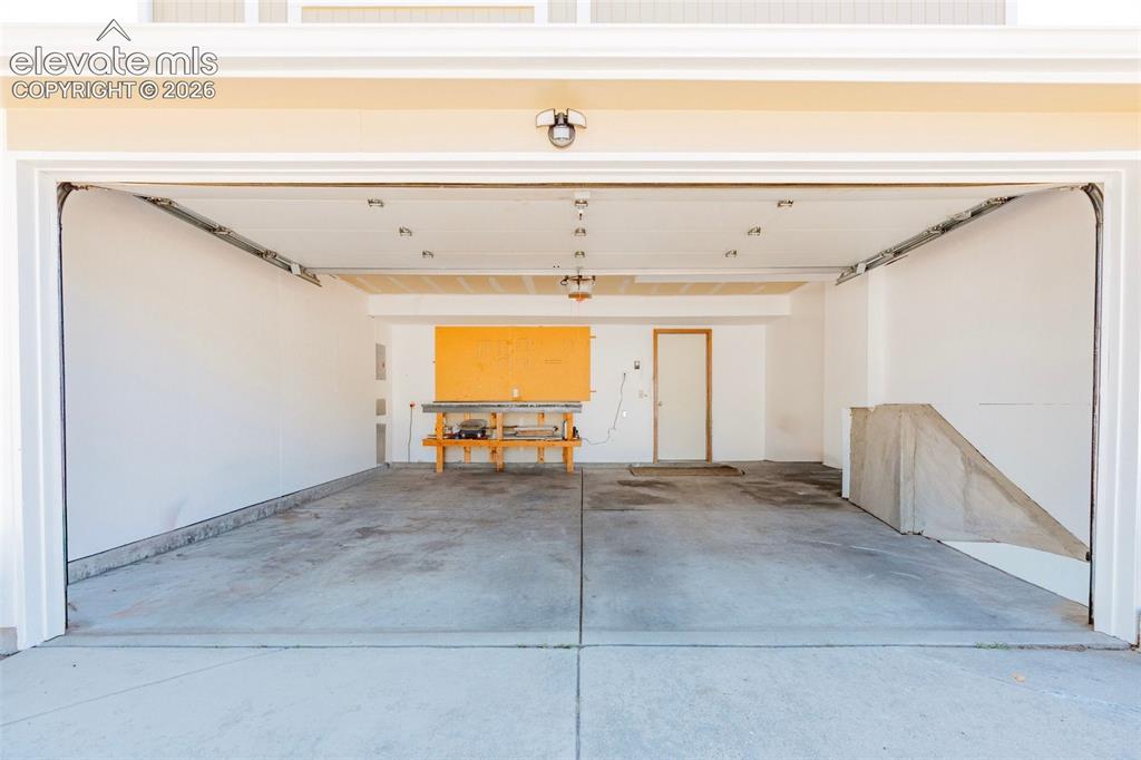 Image 27 of 33: Spacious garage featuring a concrete floor, overhead lighting, and white pa