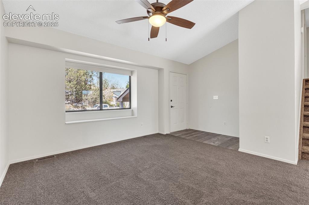 Image 5 of 33: Vaulted ceilings with a ceiling fan, carpet flooring, a large window, and w