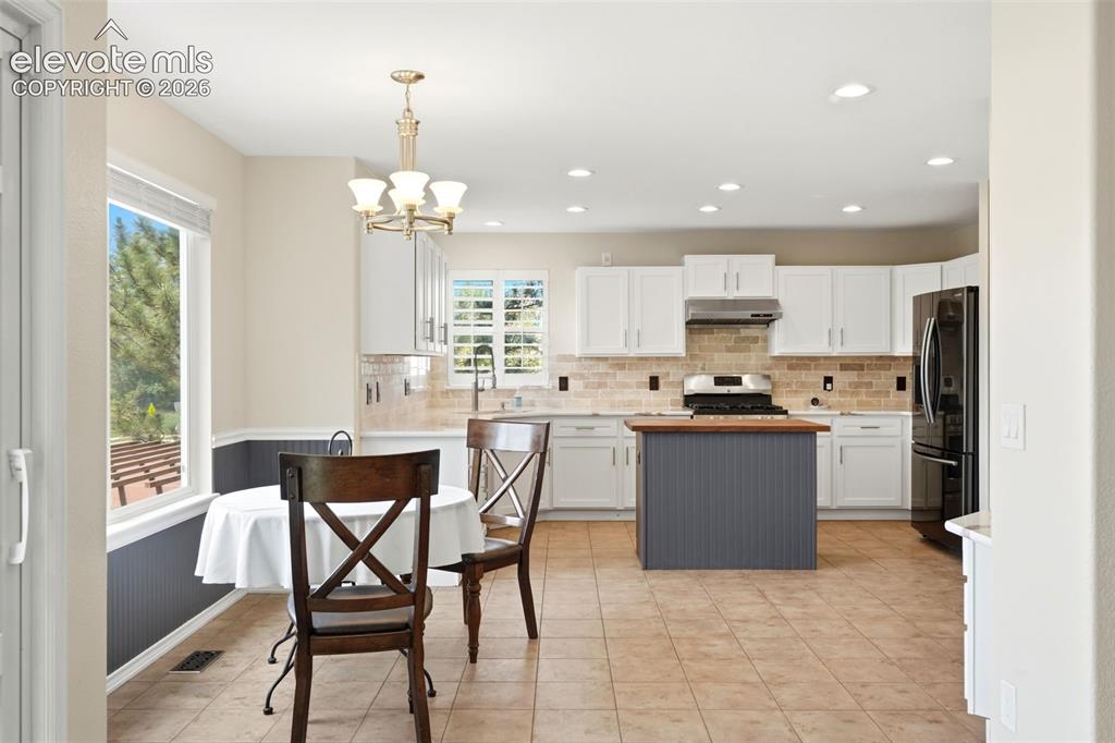 Image 10 of 43: Kitchen featuring tile flooring, white cabinetry, a central island with woo
