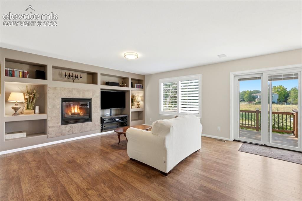 Image 11 of 43: Living area featuring wood-finish flooring, a built-in media center with a